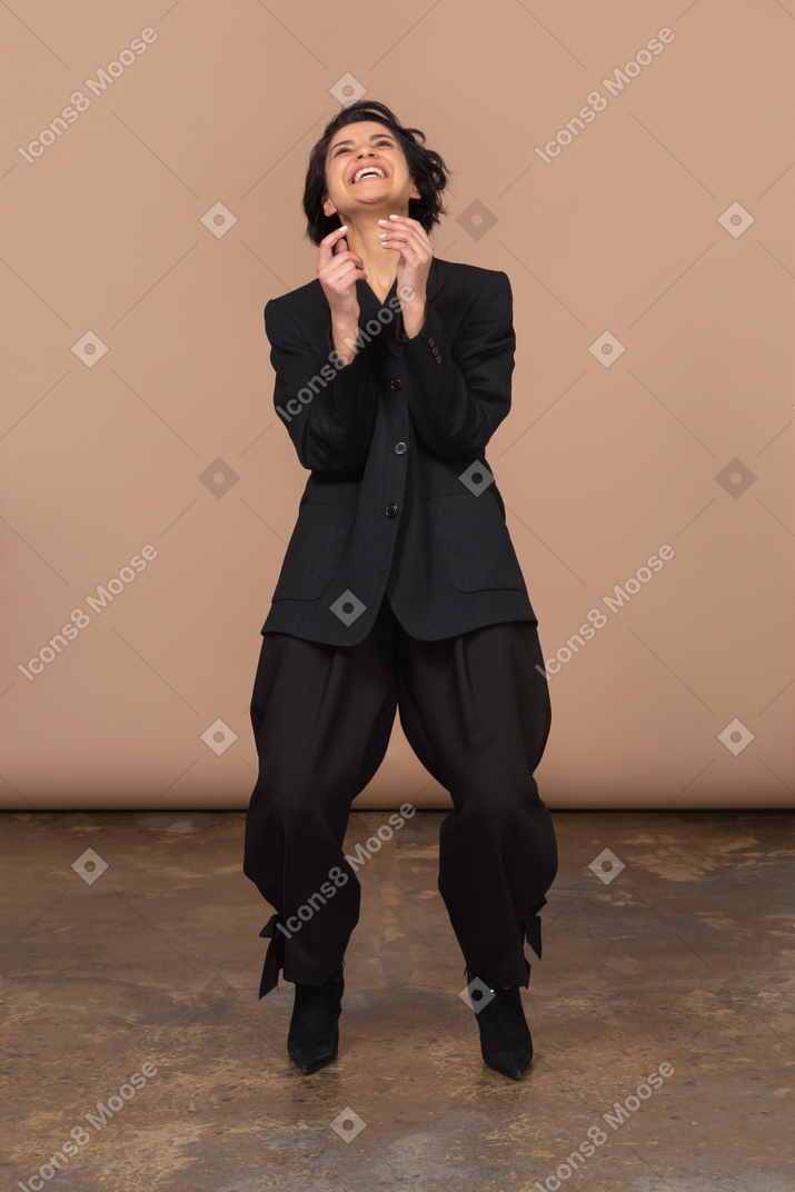 Front view of a laughing businesswoman bending knees and looking up