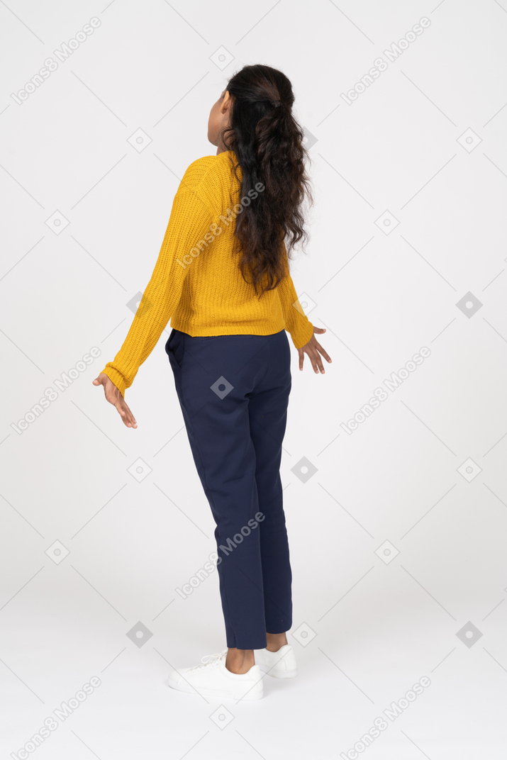 一个穿着 casua 衣服的女孩张开双臂站立的后视图