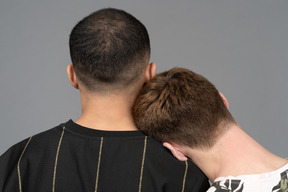 Back view of young man putting head on partner's shoulder