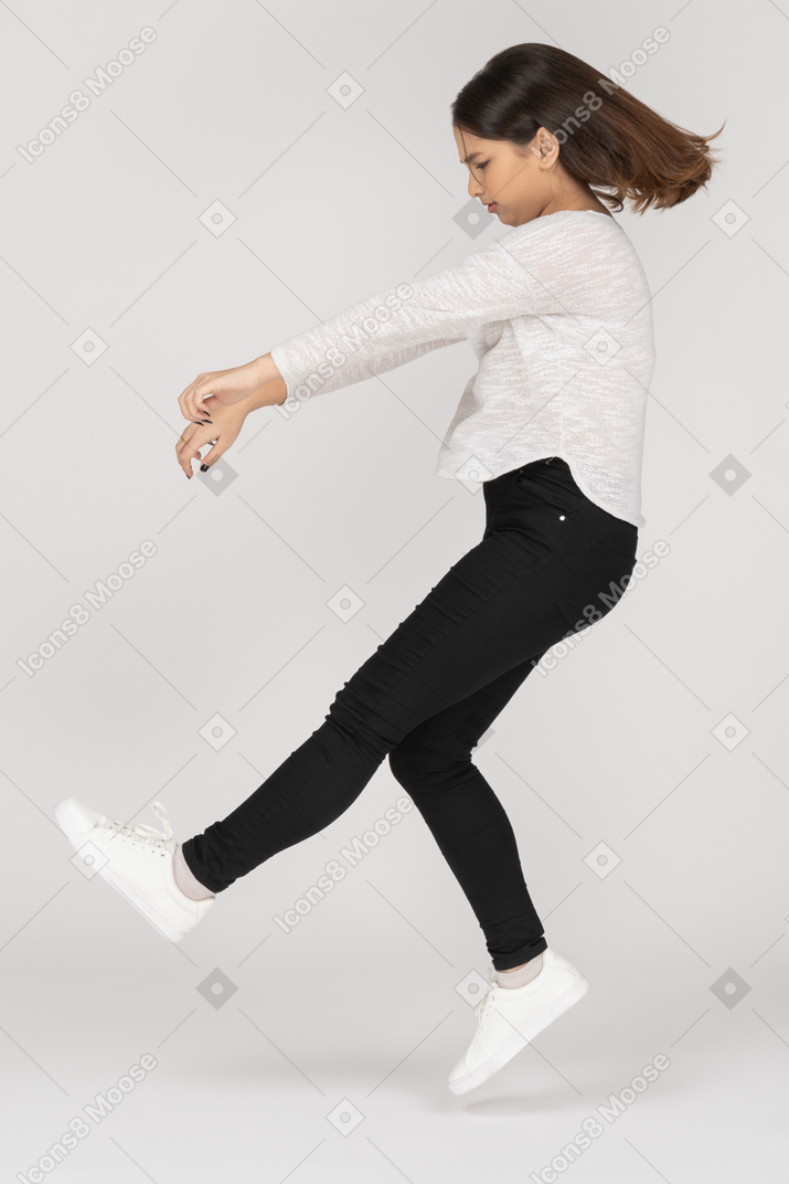 Вид сбоку прыгающей молодой индийской женщины в повседневной одежде, протягивающей руки
