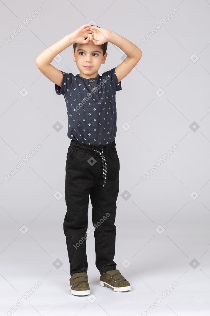 一个可爱的男孩双手放在头上摆姿势的前视图