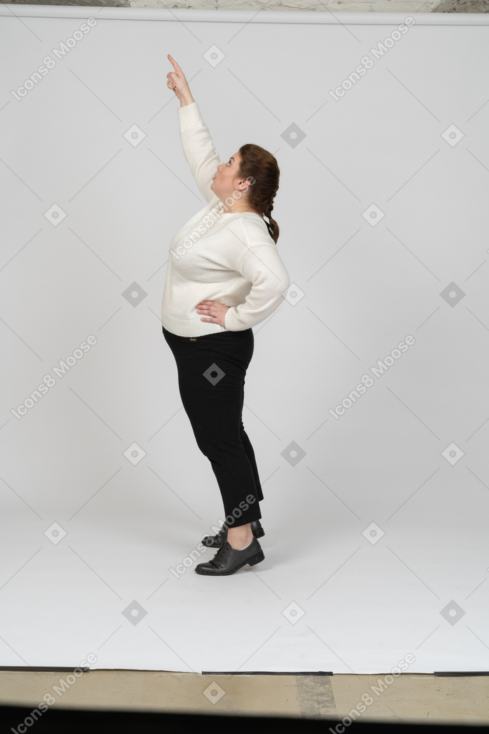 Side view of a plump woman in casual clothes standing with raised arm