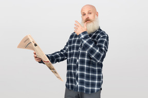 Bearded man with a newspaper looking puzzled