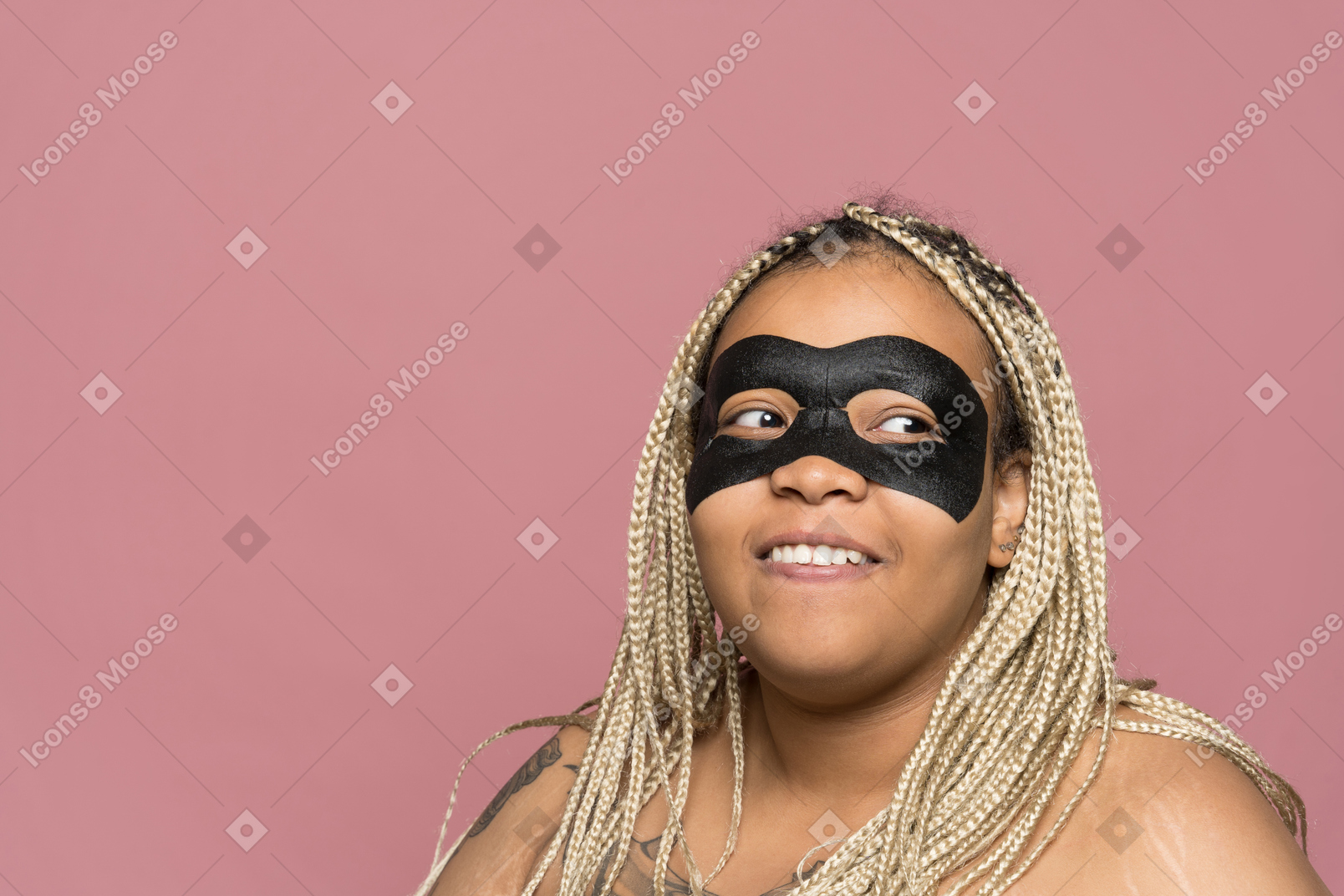 Alegre mujer afroamericana aplicando máscara de ojo negro