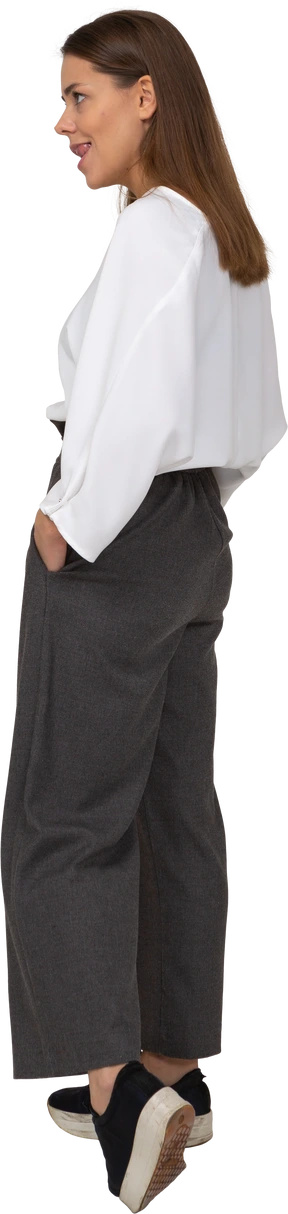 Three-quarter back view of a young lady in office clothing biting lips while walking