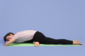 Beau jeune homme couché sur le tapis de yoga