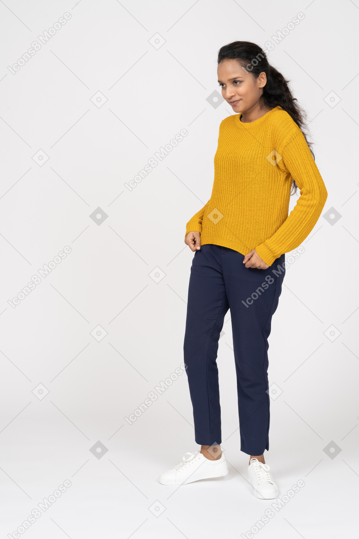 Front view of a happy girl in casual clothes posing with hands on hips