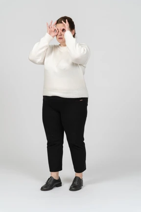 Plus size woman in casual clothes looking through imaginary binoculars