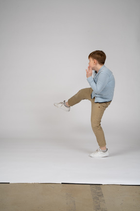 Side view of a boy kicking his leg up