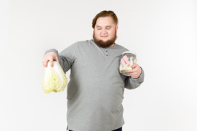 Bid bearded man choosing between cabbage and marshmallows