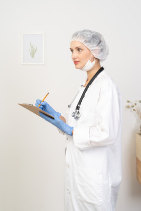 Vista laterale di una giovane dottoressa che tiene matita e tablet