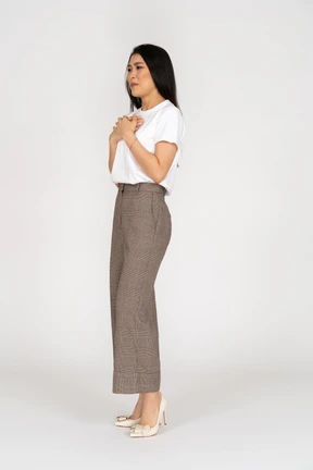 Three-quarter view of a sad young lady in breeches and t-shirt touching chest