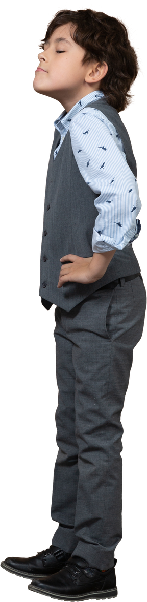 Side view of a cute boy in grey suit posing with hands on hips