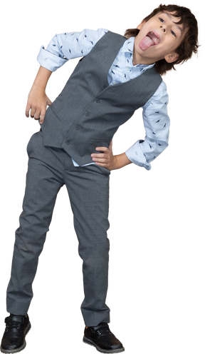 Front view of a boy in suit posing with hands on hips and showing tongue