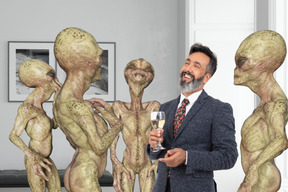 A man in a suit standing next to a group of aliens