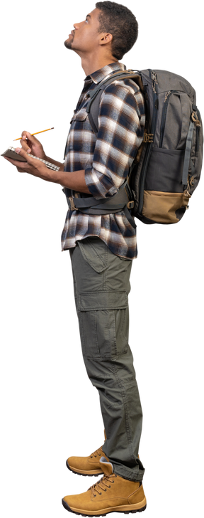 Вид сбоку на туриста с рюкзаком и блокнотом
