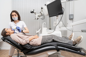 Comprimento total de uma dentista fazendo uma injeção em sua paciente em um armário de hospital