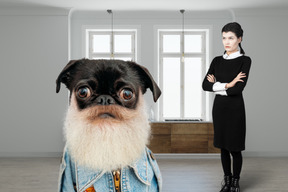 A woman standing next to a dog wearing a jean jacket