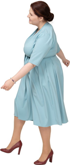 Vista laterale di una donna in abito blu che cammina