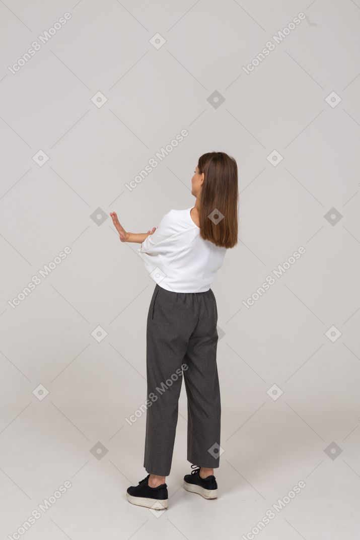 Three-quarter back view of a young lady in office clothing crossing arms