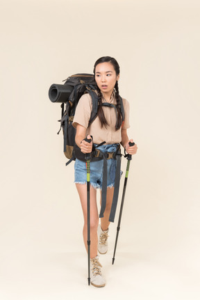 Joven excursionista mujer caminando con bastones de trekking