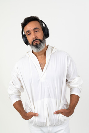 Mature man wearing headphones and holding hands in his pockets