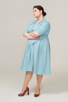Vista laterale di una donna in abito blu in posa con le braccia incrociate
