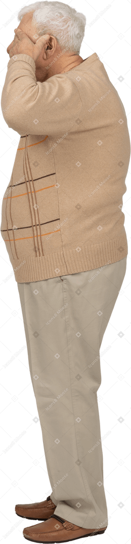 Vista lateral de un anciano con ropa informal que cubre los ojos con las manos