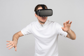 Young man in vr headset moving carefully somewhere in virtual reality