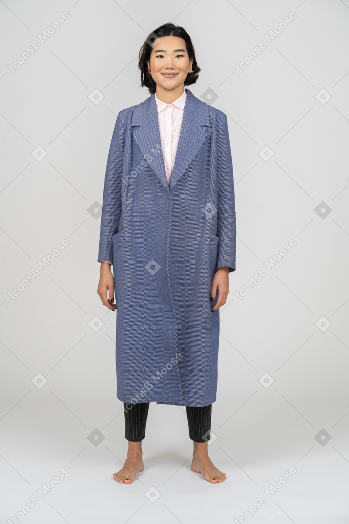 Donna sorridente in cappotto blu in piedi con le braccia ai lati