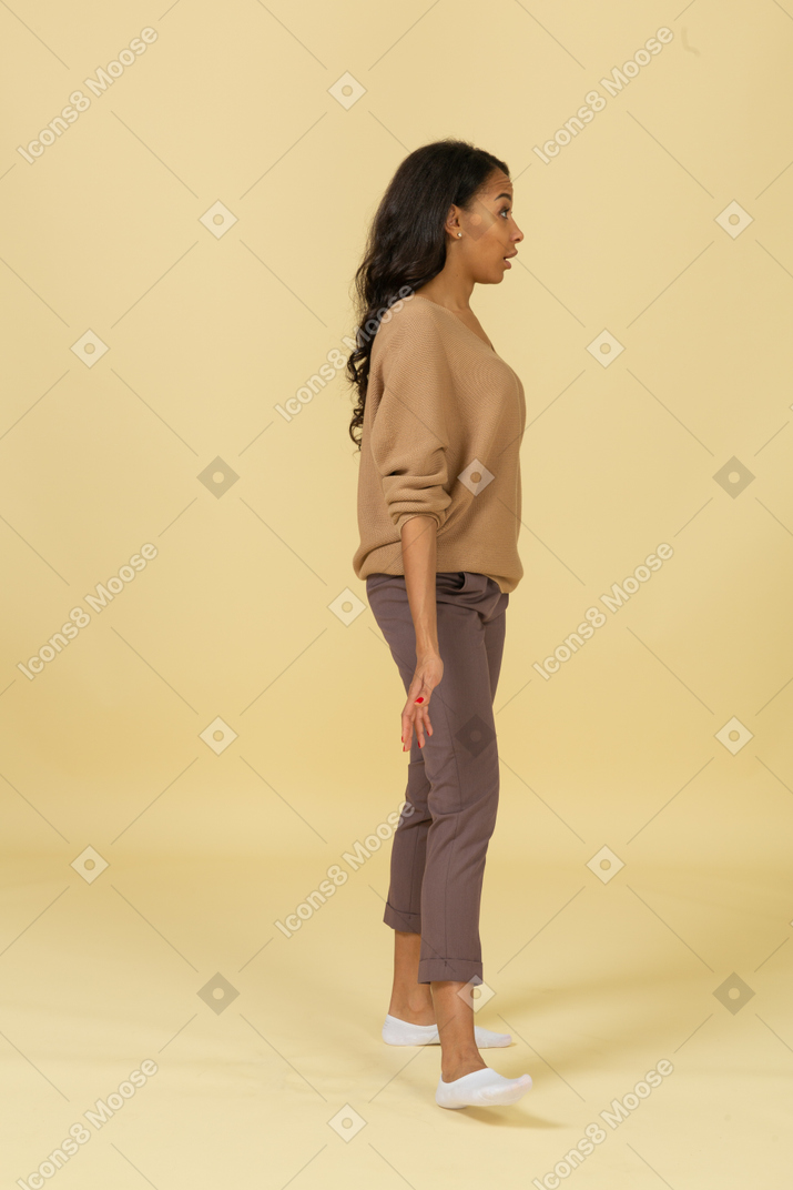Side view of a questioning dark-skinned young female outspreading her hands