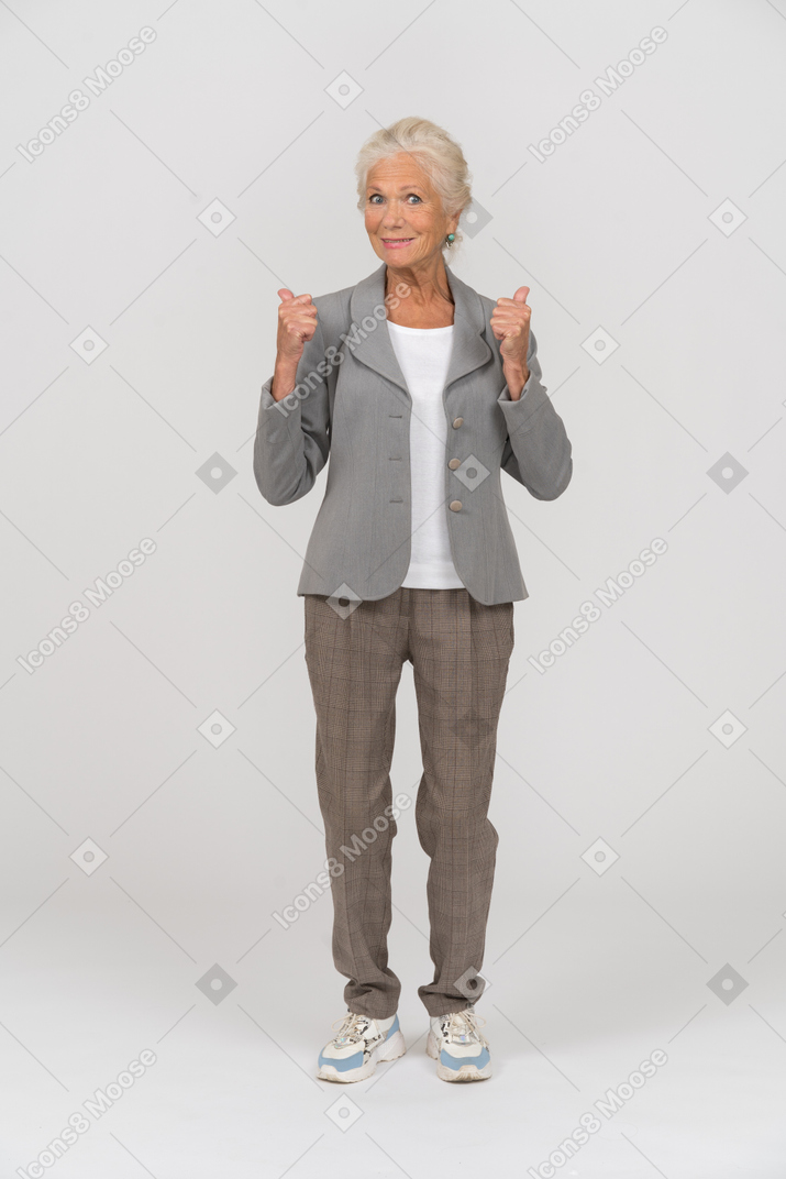 엄지손가락을 보여주는 양복을 입은 행복한 노부인의 전면 모습