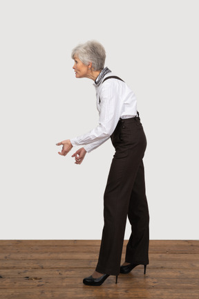 Side view of an old grimacing lady in office clothing clenching her fists