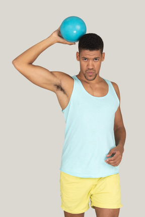 Sporty man holding a blue ball up