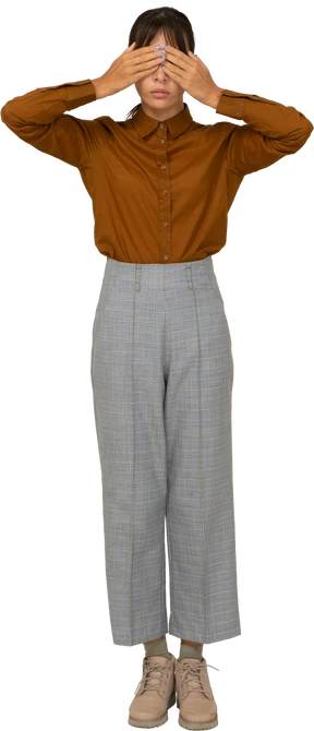 Front view of a young asian female in breeches and blouse hiding eyes