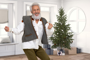 A man in a vest and bow tie dancing in front of a christmas tree