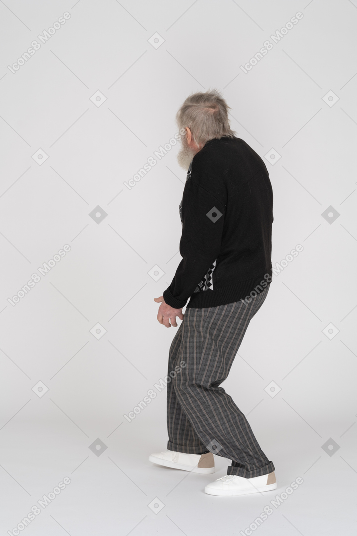 Vista lateral de un anciano caminando mirando hacia otro lado