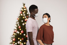 Pareja joven con máscaras están listos para la navidad