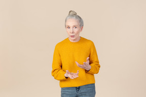 Elegante mujer mayor en un suéter de mostaza