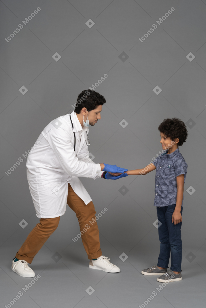 Маленький пациент и врач пожимают друг другу руки