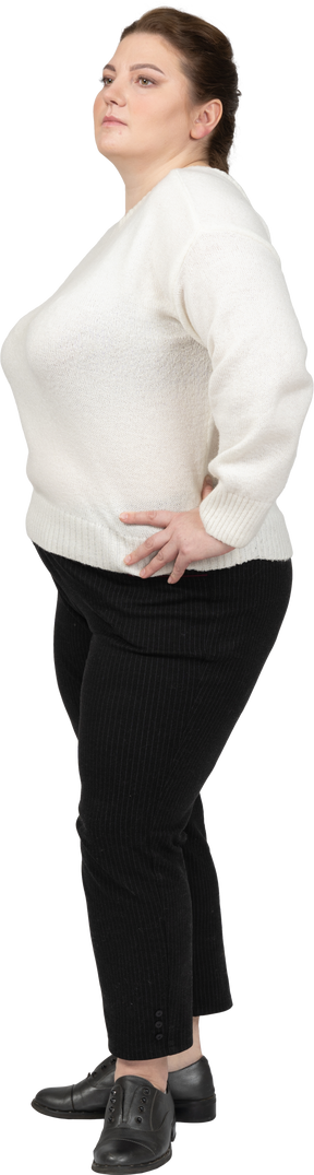 Donna grassoccia in maglione bianco in posa con le mani sui fianchi