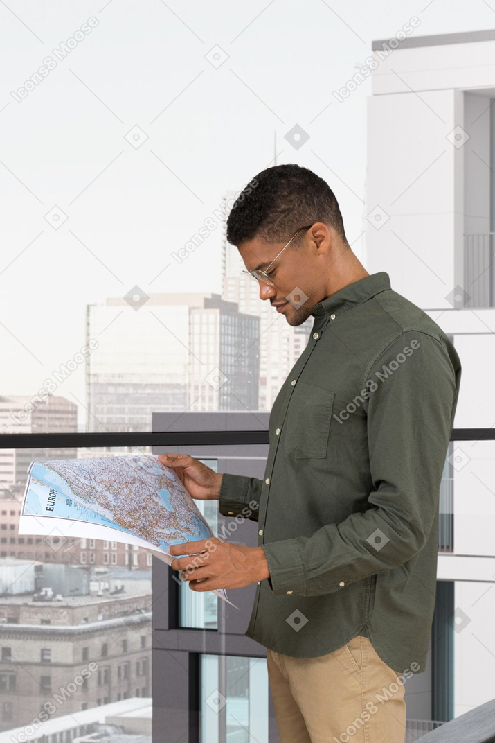 A man standing on a balcony looking at a map