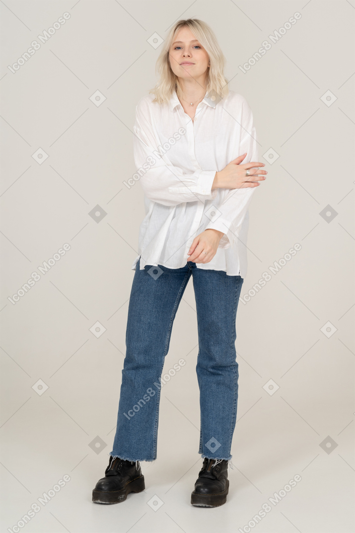 Vista frontale di una donna bionda toccando il braccio e guardando la fotocamera