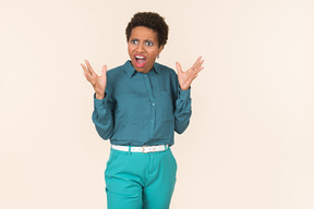 Black woman with a short haircut, wearing all blue, standing against a plain pastel background, looking emotional