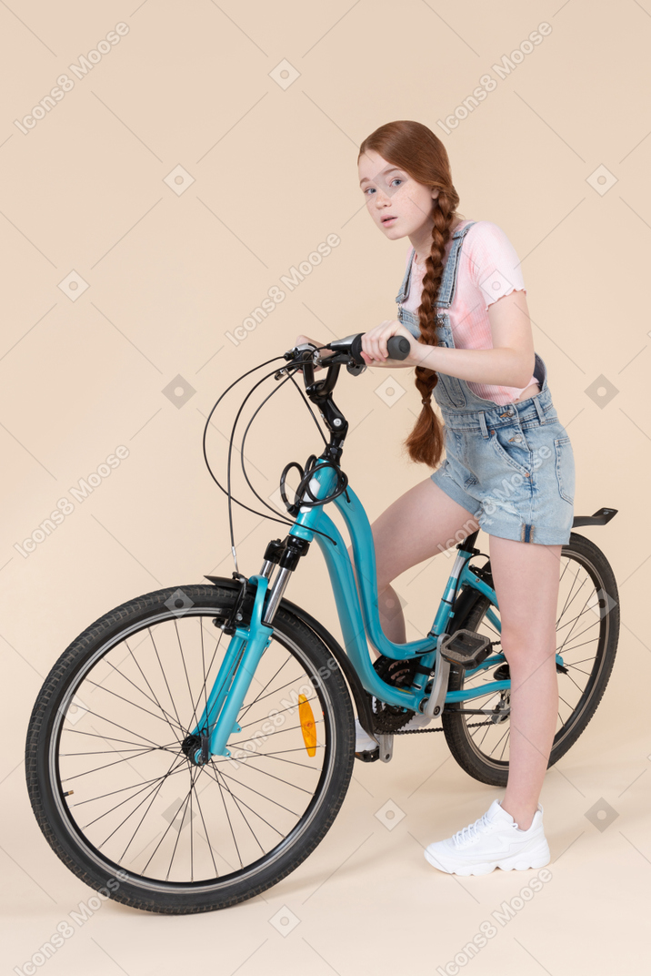 Teenage girl getting on bicycle