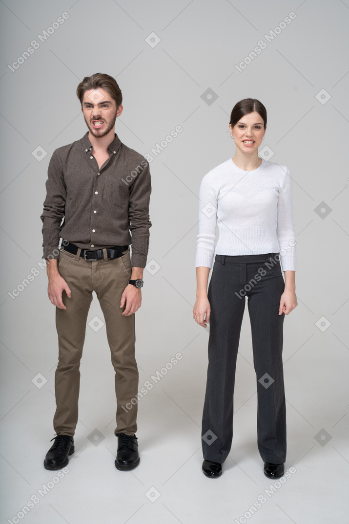 Front view of a young couple in office clothing clenching teeth