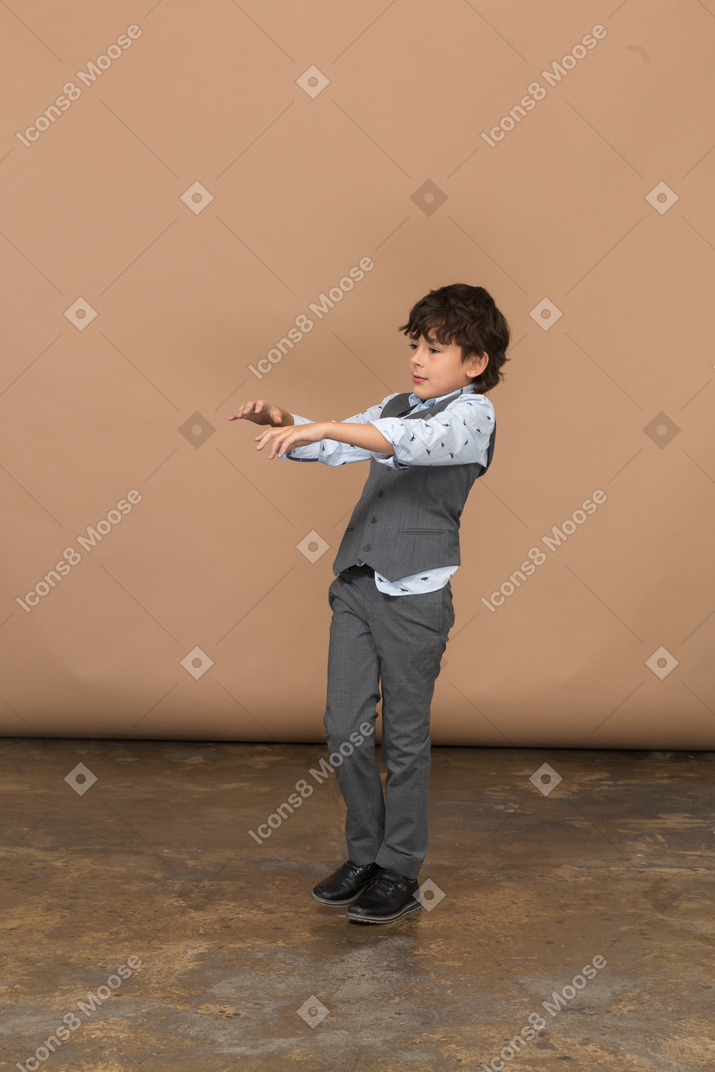 Front view of a boy in suit standing with outstretched arms