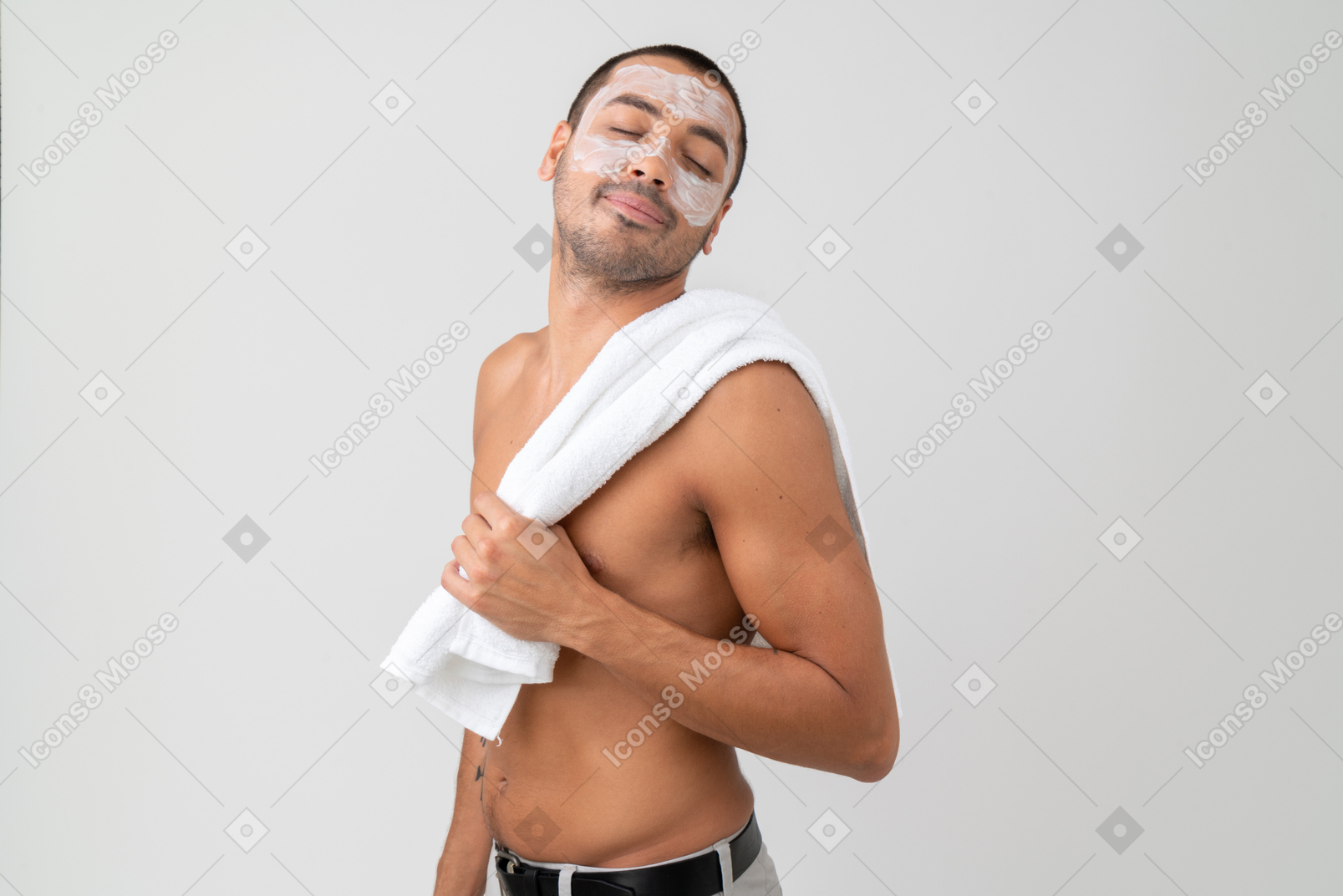 A topless man with moisturizer on his face holding a towel