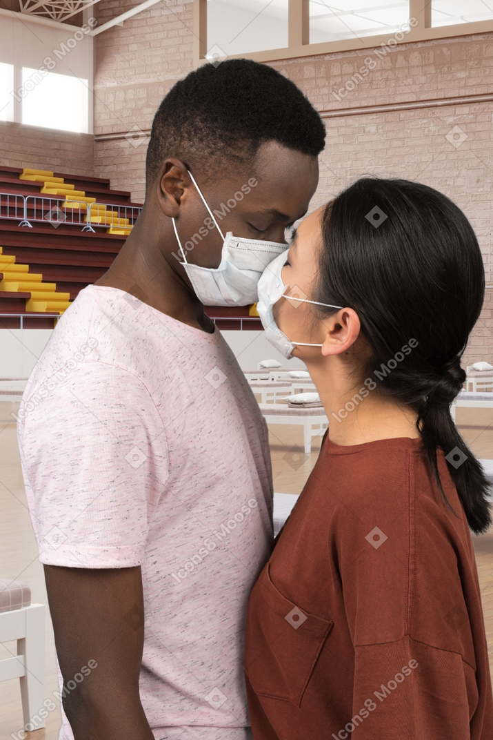 A man and a woman wearing face masks and kissing