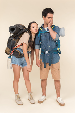 Tired looking young interracial couple of hikers